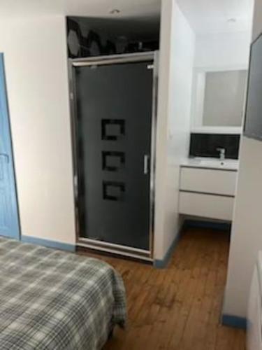 a room with a door with a bed and a sink at Tout confort T2 in La Bourboule
