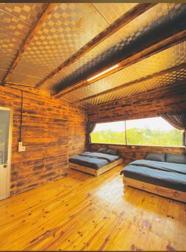 two beds in a room with wooden walls at Thông house 2 in Kon Von Kla