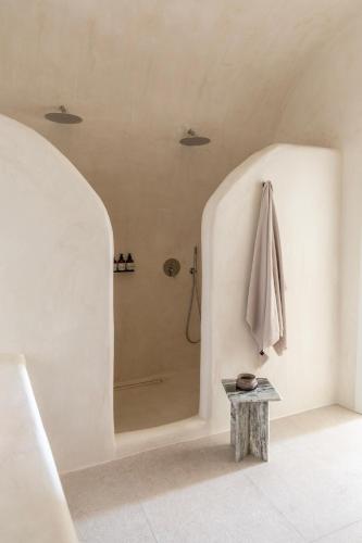 a white bathroom with a shower with a table at Istoria, a Member of Design Hotels in Perivolos