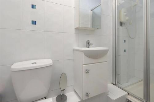 a white bathroom with a toilet and a sink at Copeland House 4 Island Wall in Whitstable