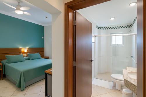 a bedroom with a bed and a bathroom with a shower at Hotel Nova York in Araçatuba