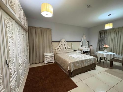 a bedroom with a bed and a table and a chair at Hotel O Recanto in Campo Mourão