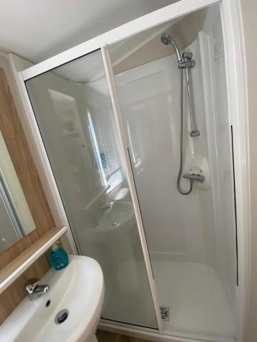 a bathroom with a shower and a toilet and a sink at Caravan no 69 in Cwm-y-glo
