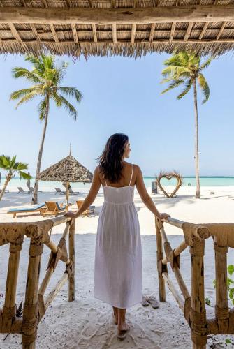 a woman in a white dress standing on the beach at Royal Mandarin Hotel & Resort Zanzibar in Pwani Mchangani