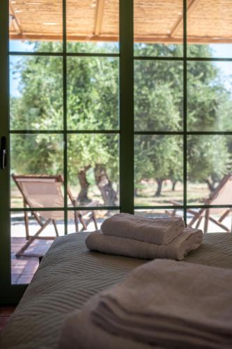 two towels on a bed in front of a window at Eleon Olive Retreat - Skourochori in Katakolo