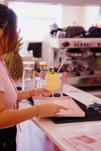a woman standing at a counter with a drink at Hugstore Pink Hotel in George Town