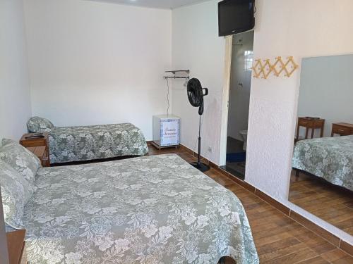a bedroom with two beds and a fan in it at Pousada Fernandes in Três Corações