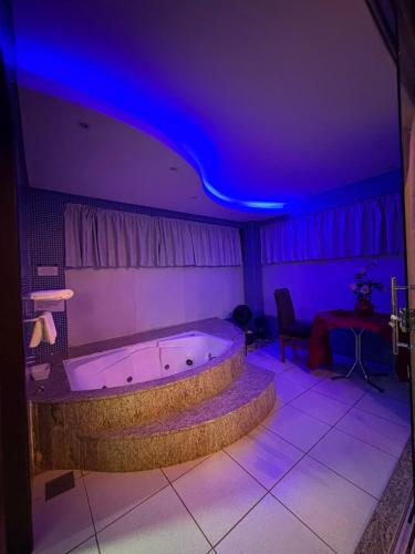 a bath tub in a room with purple lights at Hotel O Recanto in Campo Mourão