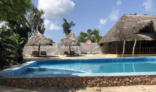 a resort with a swimming pool and two thatched umbrellas at Nanakizilodge in Mtendeni