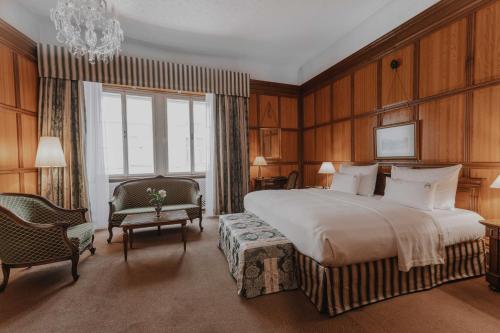 a bedroom with a bed and a chair and a chandelier at Hotel König von Ungarn in Vienna