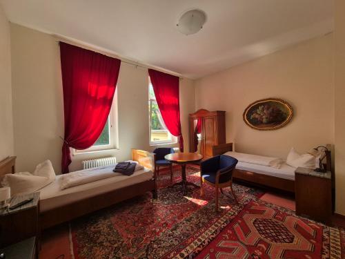 a room with two beds and a window with red curtains at PP Pension Potsdam in Potsdam