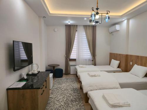 a hotel room with three beds and a television at FARIZ Hotel in Panjakent