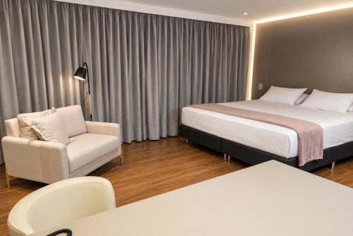 a hotel room with a bed and a chair at Hotel Greenville by Slim Hotéis in Primavera do Leste