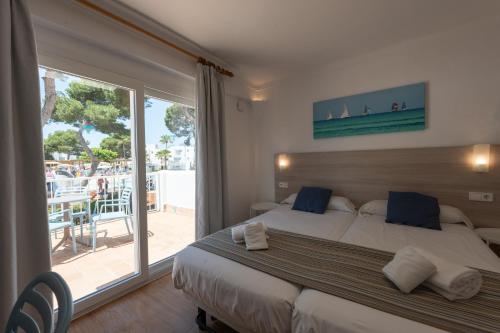 a bedroom with a large bed and a large window at Hotel Club Es Talaial in Cala d´Or
