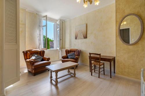 a living room with two chairs and a table and a mirror at Domaine De La Perthuiserie in Saint-Porchaire
