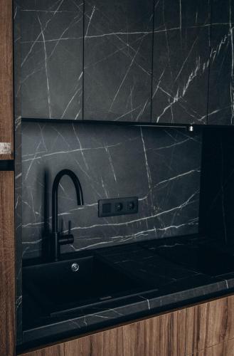 a kitchen sink with a black counter top at Клубний дім D2 in Chornomorsk