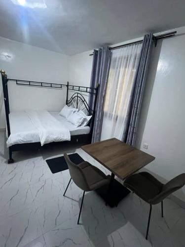 a room with a bed and a table and a table and chair at Rv delight suite in Nairobi