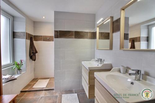 a white bathroom with a sink and a mirror at Les hauts de kergiquel in Paimpol