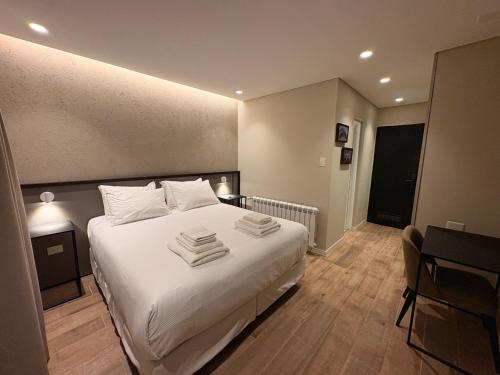 a bedroom with a white bed with towels on it at Origen Patagonia Hotel in Puerto San Julián