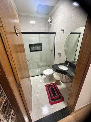 a bathroom with a toilet and a sink and a mirror at Área de Lazer DAY USE - Chácara do Danilo in Maringá