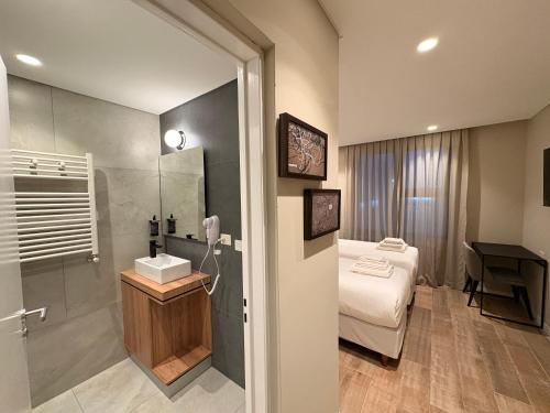 a bathroom with a bed and a sink and a shower at Origen Patagonia Hotel in Puerto San Julián