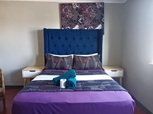 a bedroom with a purple bed with a blue headboard at SkyWags Guest House in Bloemfontein