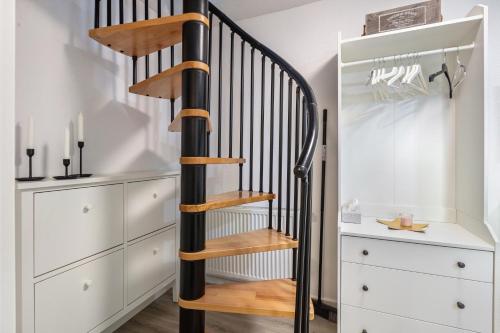 a wooden spiral staircase in a room with white cabinets at Ferienwohnung Casa Marco 1 in Grenzach-Wyhlen
