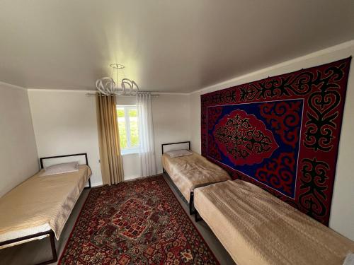 ein Zimmer mit zwei Betten und einem Teppich in der Unterkunft KölToo in Barskoon