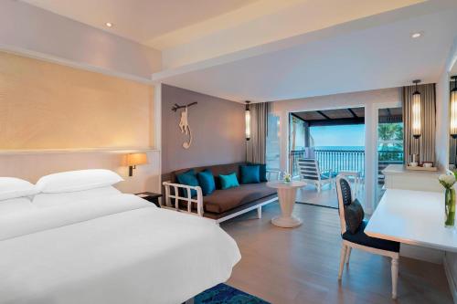 a hotel room with a bed and a living room at Sheraton Samui Resort in Chaweng Noi Beach