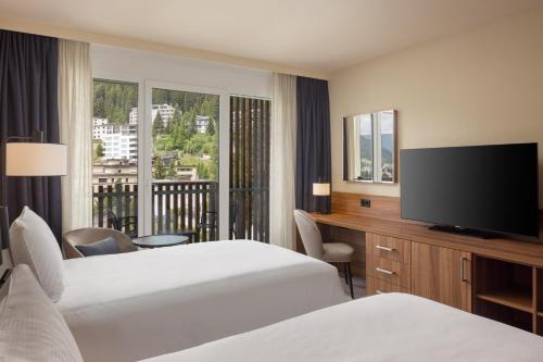 a hotel room with two beds and a flat screen tv at Hilton Garden Inn Davos in Davos
