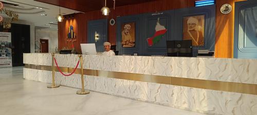 a man is sitting at a counter in a room at Al-TARABOT HOTEL in Muscat