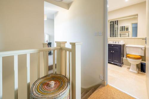 a bathroom with a staircase with a toilet and a sink at Little Tern in Brancaster