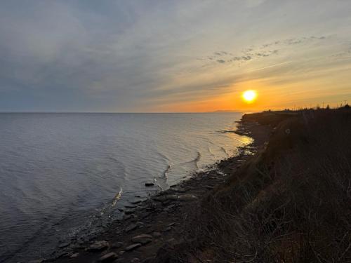 a sunset on the shore of a body of water at Waterfront & breathtaking view - Chalet du Phare in Bonaventure