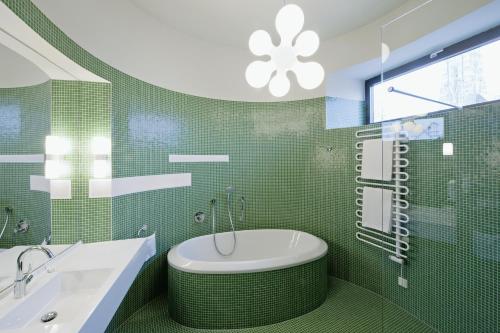 a green tiled bathroom with a tub and a sink at Hotel König von Ungarn in Vienna