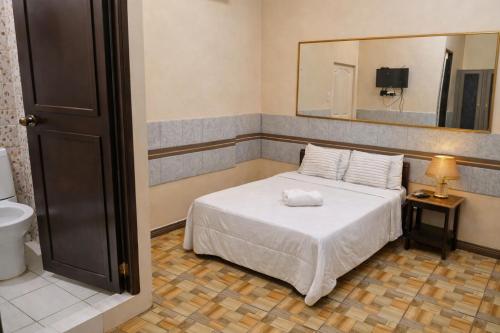 a bedroom with a white bed and a mirror at The Canley Boutique Hotel Ortigas Pasig Metro Manila in Manila