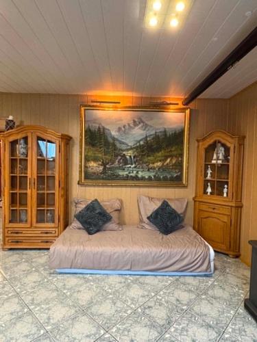 a bedroom with a bed with a painting on the wall at Lila Central Apartman in Balatonlelle