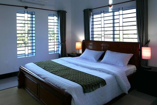 Anou Home - Guesthouse في سيام ريب: غرفة نوم بسرير كبير مع نافذتين