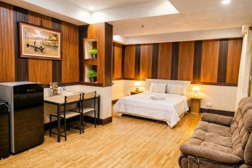 a bedroom with a bed and a desk and a couch at The Canley Boutique Hotel Ortigas Pasig Metro Manila in Manila