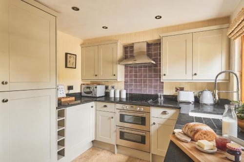 a kitchen with white cabinets and a table with bread on it at Squirrel Barn in Moreton in Marsh