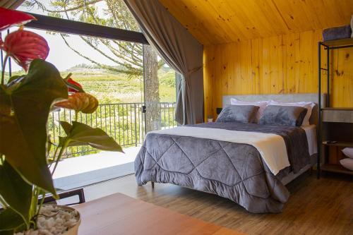 a bedroom with a bed and a large window at Cappio Pousada e Lazer in Bento Gonçalves