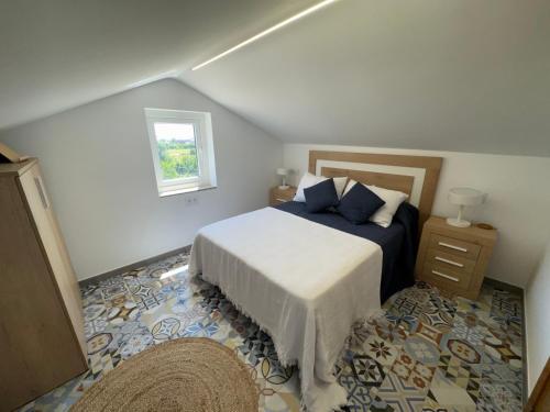 a bedroom with a bed with blue pillows and a window at Carimar, a mirada da ría in Boiro
