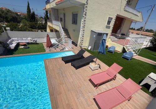 a backyard with a pool and chairs and a house at Moradia com escada, Jardim e piscina, 3Kms Praia in Almada