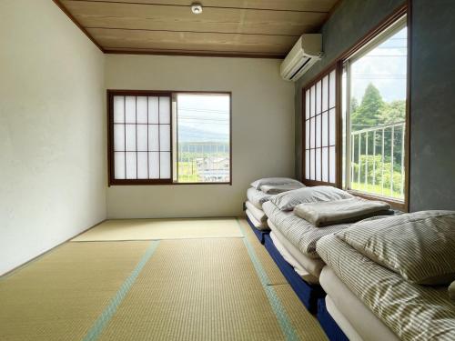 three beds in a room with two windows at ゲストハウス紗乃葉 - Suzunoha in Bōchū