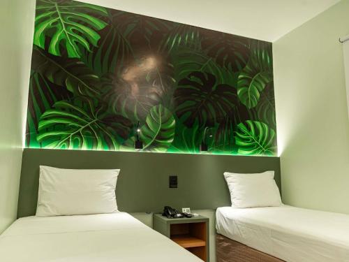 two beds in a room with a painting on the wall at ibis Styles Belém do Pará in Belém