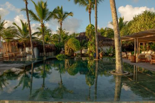 a pool at a resort with palm trees at Pousada Vila do Mar in Caraíva