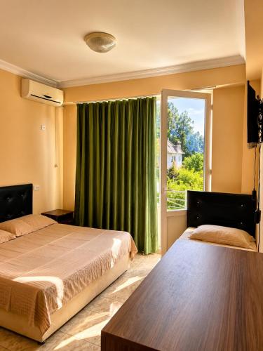 a bedroom with two beds and a window with green curtains at Mziuri Guest House in Ureki