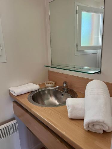 a bathroom with a sink and a mirror and towels at SAS Le Bataillet in Montégut