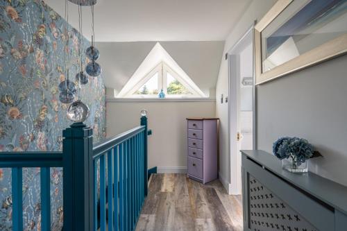a hallway with a blue staircase with a window at Otterpoint Waterfront & Pool Retreat in Tayvallich