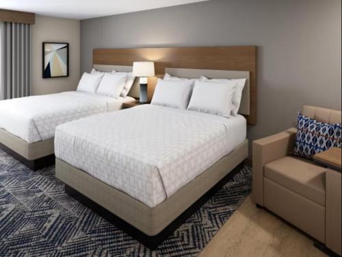 a hotel room with two beds and a chair at Candlewood Suites Rowlett - Lake Ray Hubbard by IHG in Rowlett