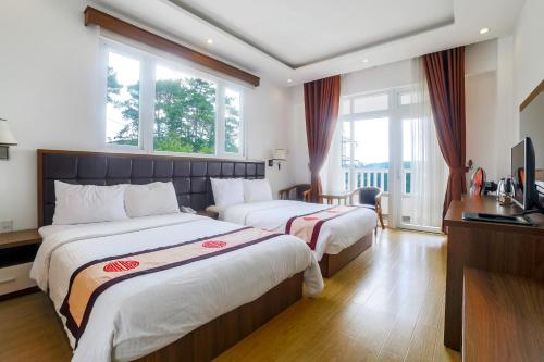 a hotel room with two beds and a television at Nhật Vy 1 Đà Lạt in Ấp Ða Lợi
